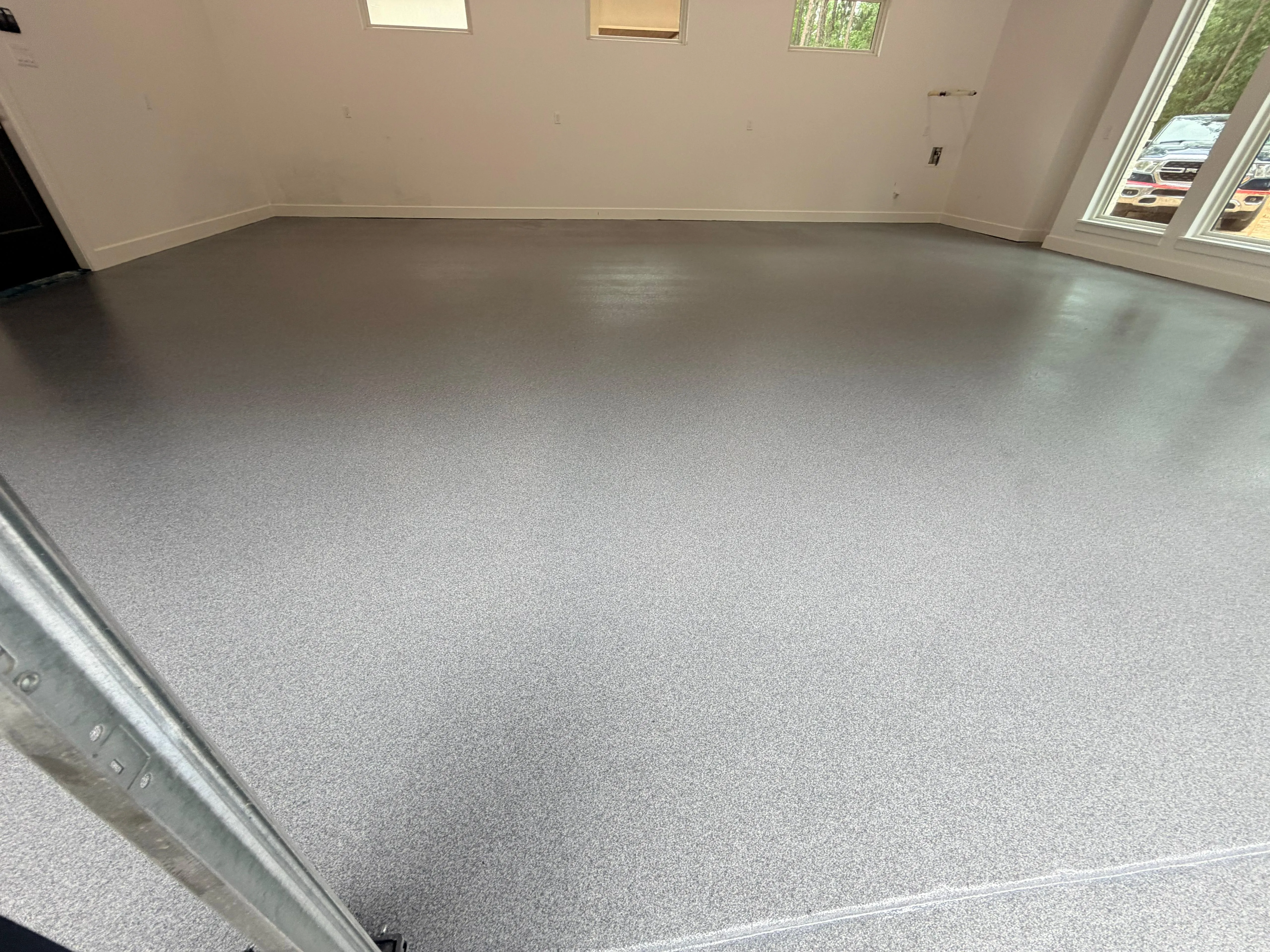 Gray flake epoxy floor in a finished Houston garage, daylight through the windows