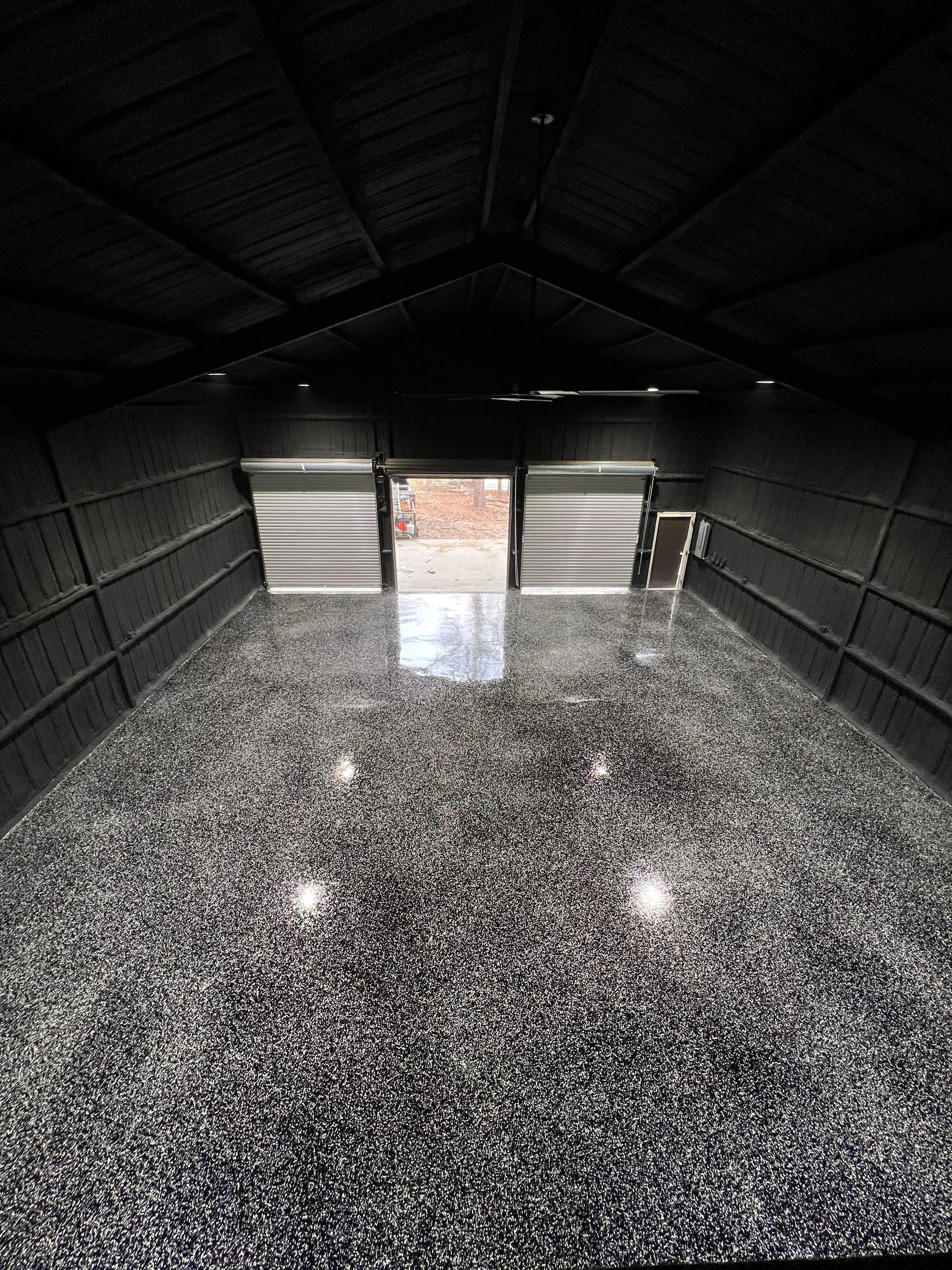 Flake epoxy floor running the length of a metal building to its roll-up loading doors